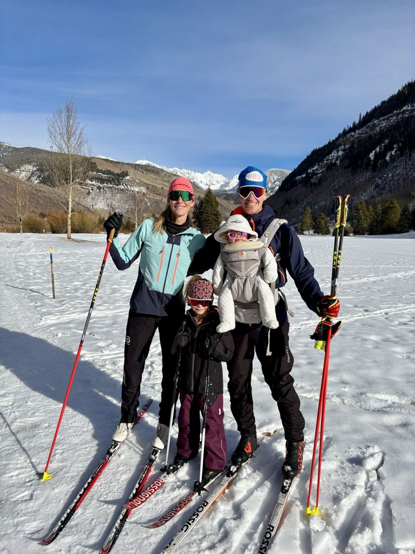 Family Nordic skiing with a baby in a chest carrier