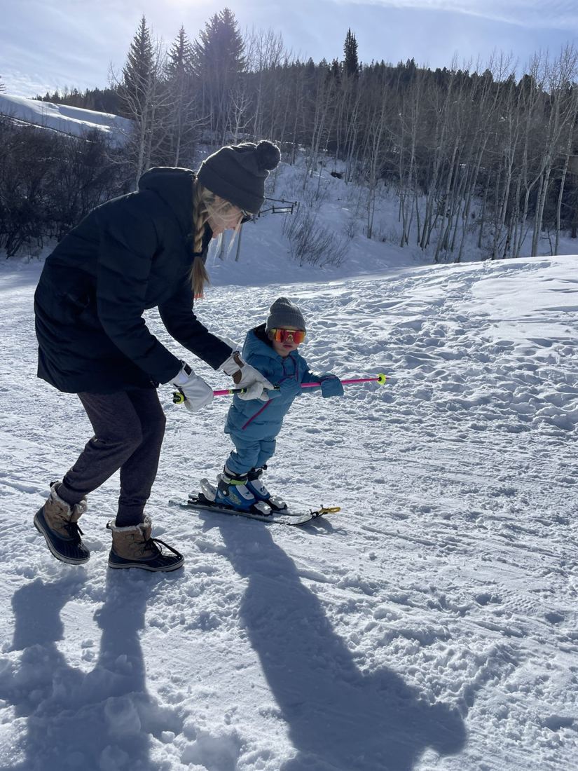 Toddler holding a ski pole like a handlebar